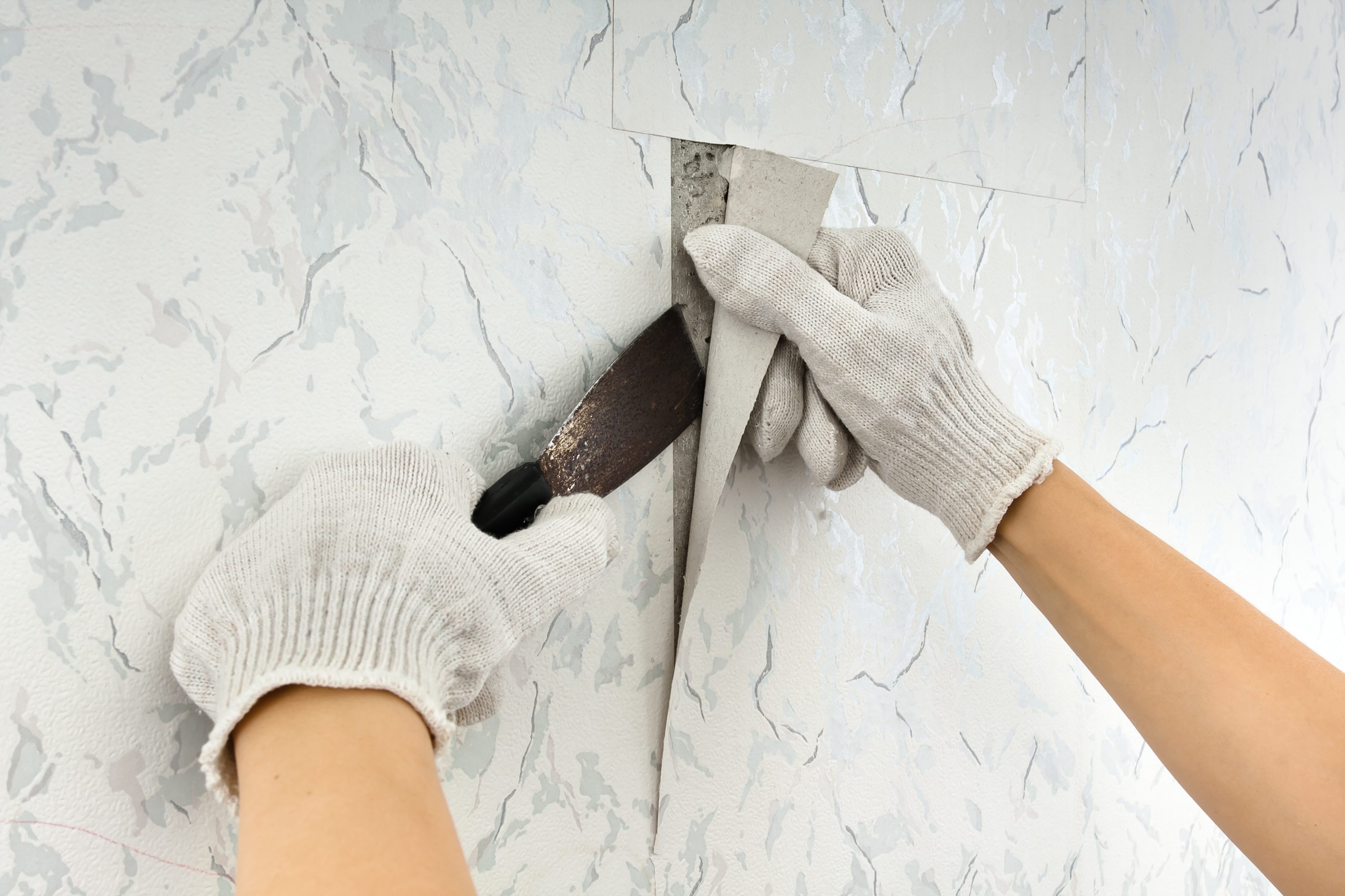 removing old wallpapers from wall with spatula during repair